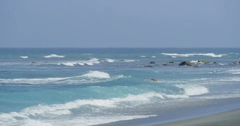 Slow motion shot of sea waves on white sandy beach with rocks, sunny day, Japan Stock Footage 125828150