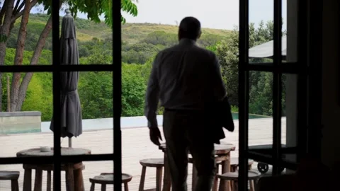 Slow motion shot of a senior man walking out a door towards a garden pool Stockbeeldmateriaal 284316644