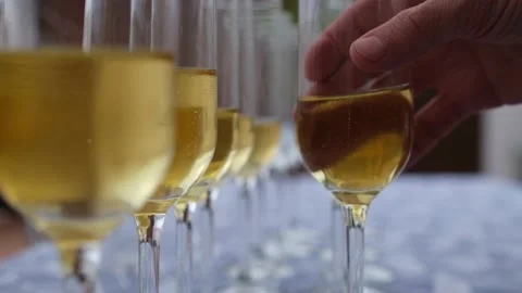 Slow motion shot of several glasses filled with champagne and a person's hand pi 库存影片 232184496