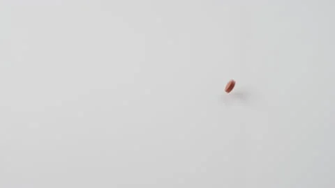 Slow motion shot of several red pills dumping out onto a white surface 스톡 동영상 153092451
