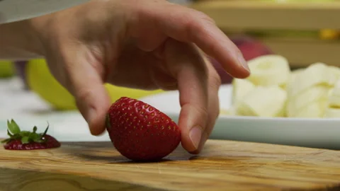 Slow motion shot of sharp knife slicing up single strawberry Stock Footage 341226763
