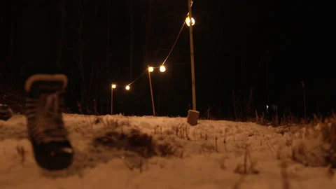 Slow motion shot of skates walking through snow at night to pond Stock Footage 147409510