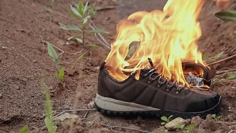 Slow motion shot of sneakers burning on the ground in daylight Stock Footage 310627797