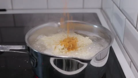 Slow motion shot of spice mix dropped on noodles in a pot Video stock 332684469