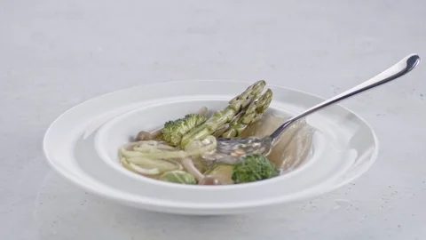 Slow motion shot of a spoon being dropped into a plate with vegetable soup. Stock Footage 103983365
