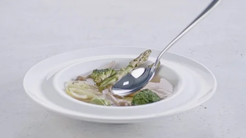 Slow motion shot of a spoon being dropped into a plate with vegetable soup. Stock Footage 103983367
