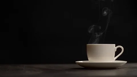 Slow motion shot of steaming cup of coffee over black background Video stock 98975156