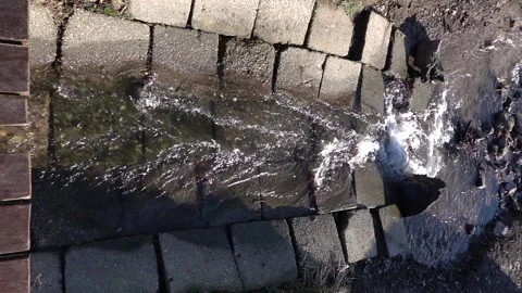 Slow motion shot of a stream flowing through a concrete chute into a lake Stock Footage 230235159