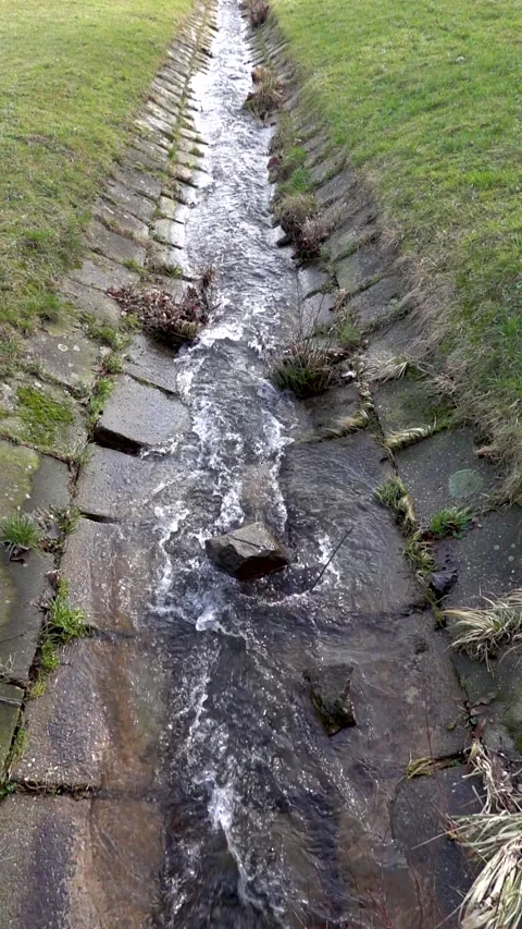 Slow motion shot of a stream flowing through a concrete chute into a lake Stock Footage 267436517