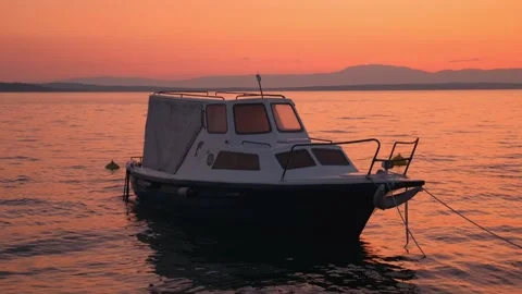 Slow motion shot: Sunset by the sea. Fishing boat sways in the waves. 4k. Slow Stockbeeldmateriaal 132014444