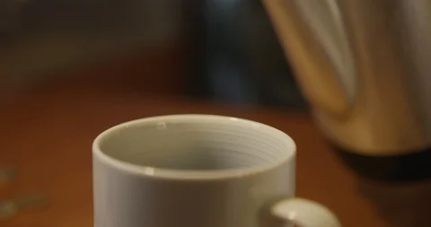 Slow motion shot of tea being poured from tea pot into mug on wooden table Stock Footage 124716588
