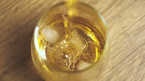 Slow motion shot top view of whiskey pouring into a glass with ice cubes. Stock Footage 196676587