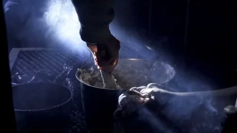 Slow motion shot of torch lit hand stirring pot on camp fire Stock Footage 81565129