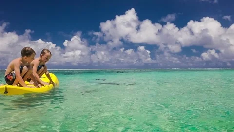 Slow motion shot of two boys jumping of canoe to tropical ocean Stock Footage 73124610