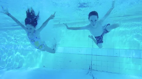 Slow motion shot of two kids diving into a swimming pool Stock Footage