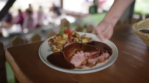 Slow motion shot of a waiter serving traditional european food in an outdoor Stock Footage 328820667