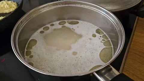 Slow motion shot of water boiling with rice in pot in restaurant kitchen. Stock Footage 303378174