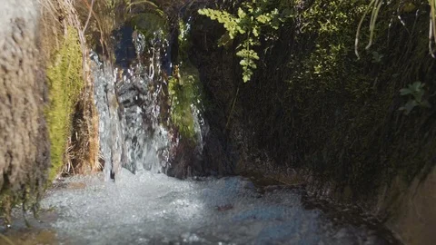 Slow motion shot of water falling of a tiny waterfall into a tiny river on Stock Footage 104744829