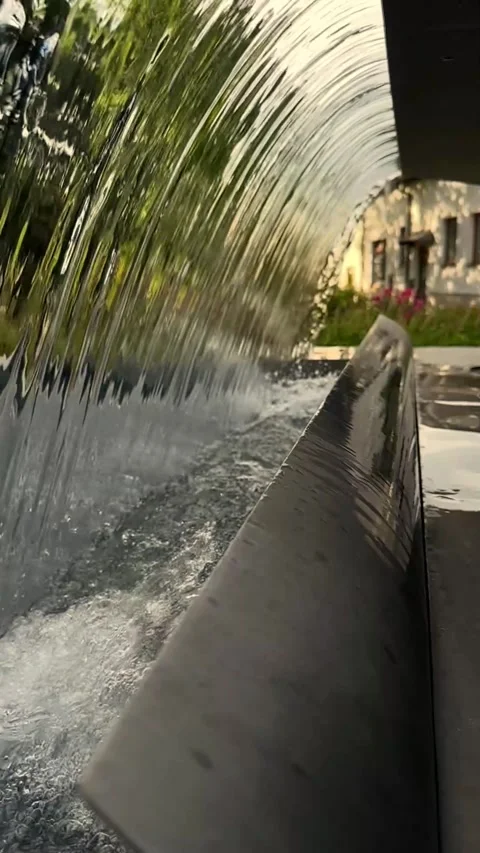 Slow-motion shot of water flowing from a fountain near a beautiful house with Видео 343911534