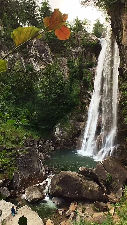 Slow-motion shot of a waterfall between brown rocks and lush green forest Stock Footage 248378083