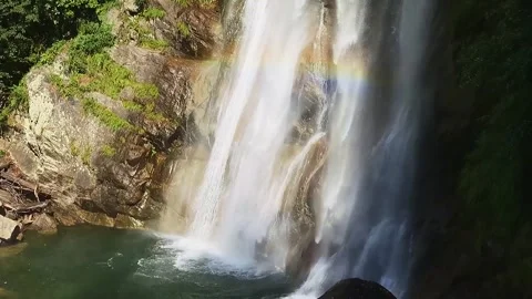 Slow-motion shot of a waterfall between brown granite rocks and green forest Video stock 248378956