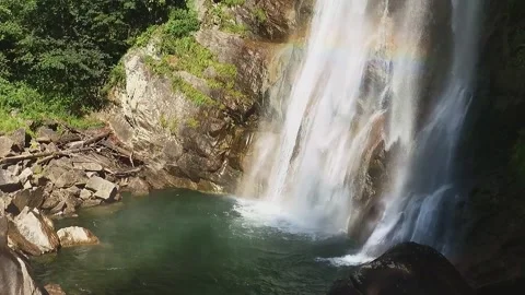 Slow-motion shot of a waterfall between brown granite rocks and green forest Stock Footage 248378987