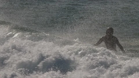 Slow motion shot of wave that momentarily engulfs surfer sitting on her board. Stock Footage 231478793