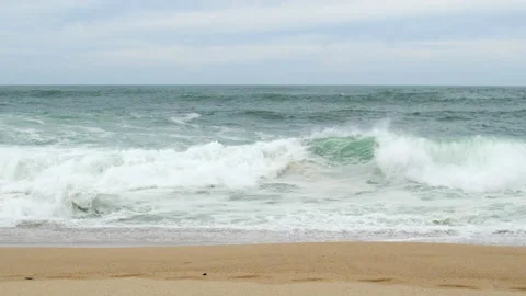 Slow motion shot of waves forming and then breaking on sandy beach in winter Stock Footage 274176091