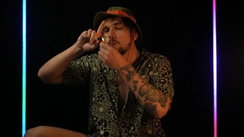 Slow motion shot of white dude in bucket hat smoking weed from a metal pipe Stock Footage 199092899