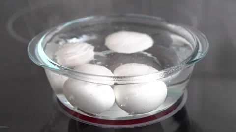 Slow motion shot of white eggs boiling in a transparent glass pot on an ele.. Stock Footage 254730077