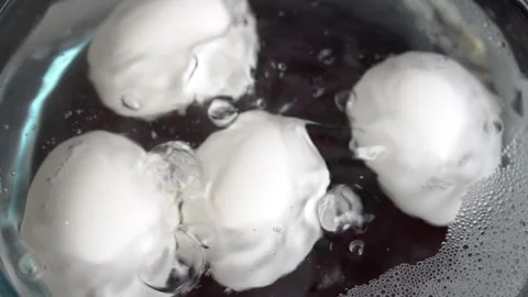 Slow motion shot of white eggs boiling in a transparent glass pot on an ele.. Stock Footage 255460967