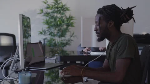 Slow motion shot of young black guy working at desk on computer in office Stock Footage 208743783