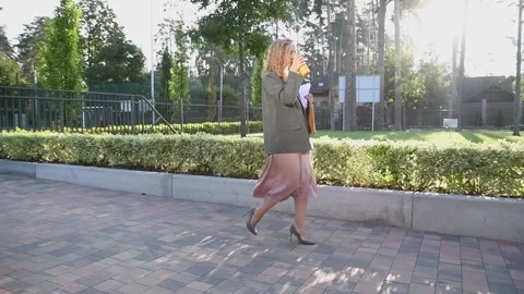 Slow motion shot of a young blonde business woman walking and drinking coffee Vídeo Stock 332609833