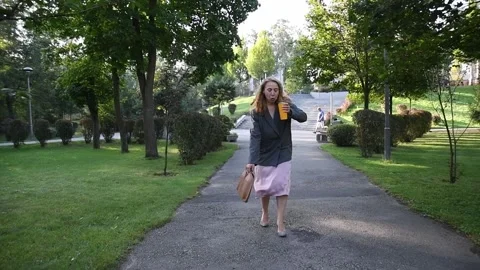Slow motion shot of a young blonde woman walking in a park 库存影片 333058501