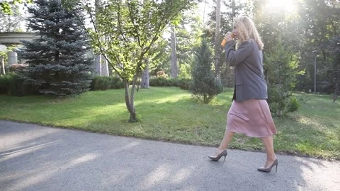 Slow motion shot of a young blonde woman walking through a park Vídeo Stock 333058666