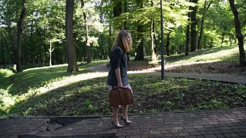 Slow motion shot of a young blonde woman walking through a park Stock Footage 333070403