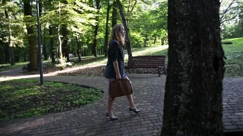 Slow motion shot of a young blonde woman walking through a park Vídeos de archivo 333070412