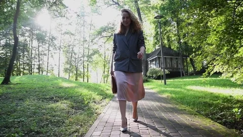 Slow motion shot of a young blonde woman walking through a park Vídeos de archivo 333070428