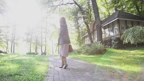 Slow motion shot of a young blonde woman walking through a park Vídeos de archivo 333070437
