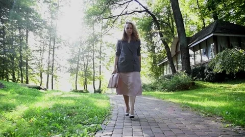 Slow motion shot of a young blonde woman walking through a park Vídeos de archivo 333070458