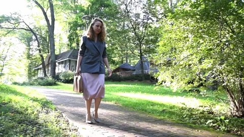 Slow motion shot of a young blonde woman walking through a park Vídeos de archivo 333070465