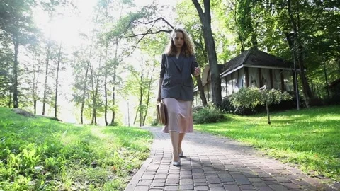 Slow motion shot of a young blonde woman walking in a park Video stock 333070489
