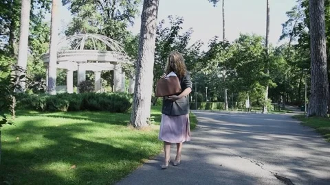 Slow motion shot of a young blonde woman walking through a park Vídeos de archivo 333070631