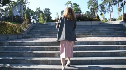 Slow motion shot of a young blonde woman walking up stairs in a park Vídeos de archivo 333070720