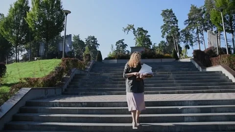 Slow motion shot of a young blonde woman walking down stairs Vidéo 333070775
