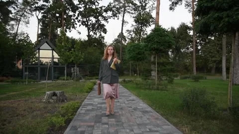 Slow motion shot of a young blonde woman walking through a park Vídeos de archivo 333070922