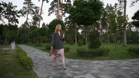 Slow motion shot of a young blonde woman walking through a park Vídeos de archivo 333070926