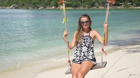 Slow motion shot of a young happy smiling woman having fun on a swing on beach Stock Footage 74642642