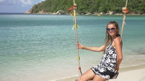 Slow motion shot of a young happy smiling woman having fun on a swing on beach Stock Footage 74642685