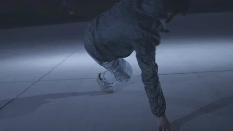 Slow motion shot of young islamic guy in jacket break dancing on dim lit stage Stock Footage 211869996